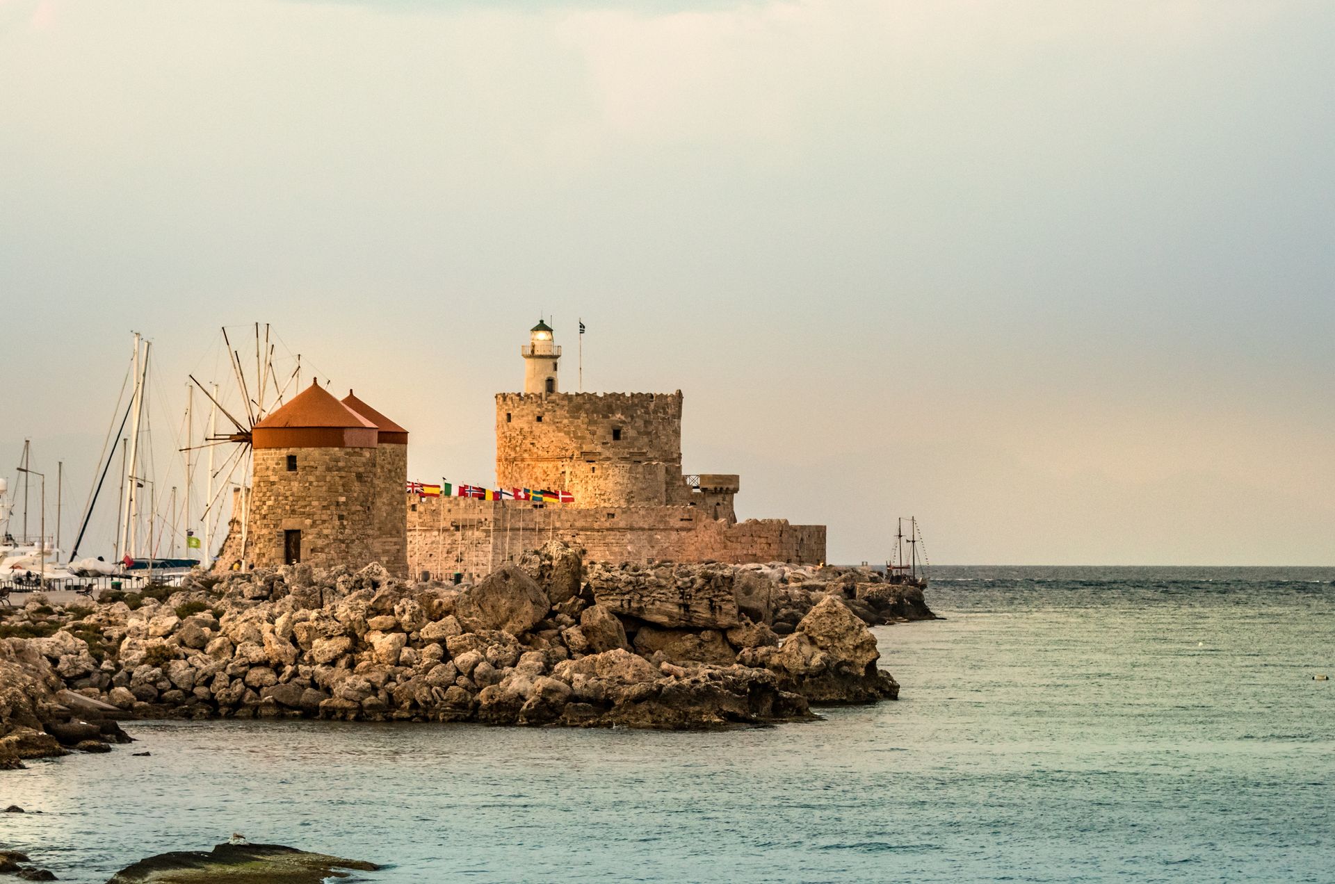 Windmills And The Lighthouse At Mandraki Harbour, Rhodes, Greece